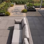 Terras met grijze tegels, rotan loungebank en grindtuin met Tambour Antraciet waalformaat