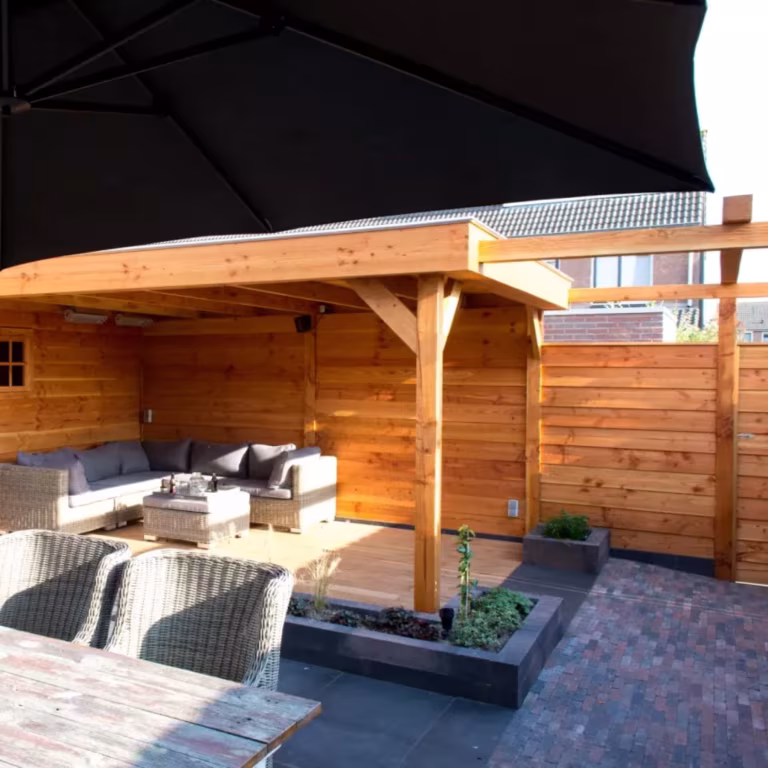 Houten overkapping met loungeset, zwarte parasol en plantenbak op Tambour Brons waalformaat