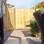 Tuin met houten poort, rotan stoel en pad van Tambour Brons waalformaat