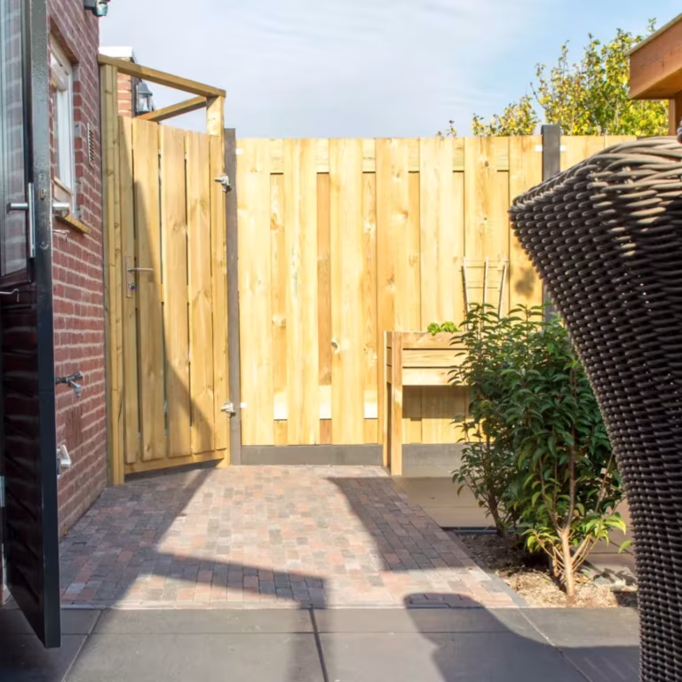 Tuin met houten poort, rotan stoel en pad van Tambour Brons waalformaat