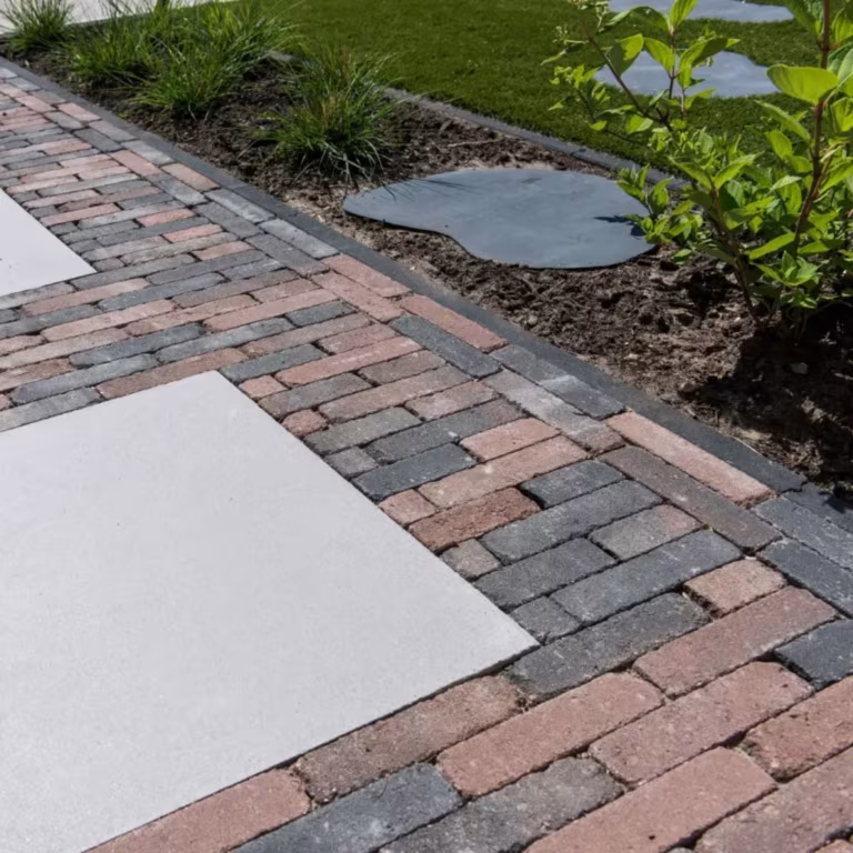 Pad van Tambour Brons waalformaat met lichte tegels en stapstenen langs gras en struiken