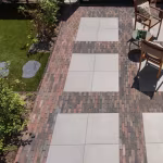 Tuinpad met lichte tegels omlijst door Tambour Brons waalformaat, gazon en tuinstoelen