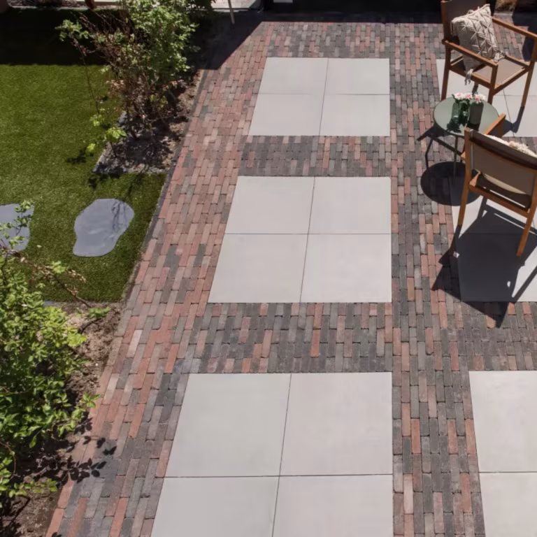 Tuinpad met lichte tegels omlijst door Tambour Brons waalformaat, gazon en tuinstoelen