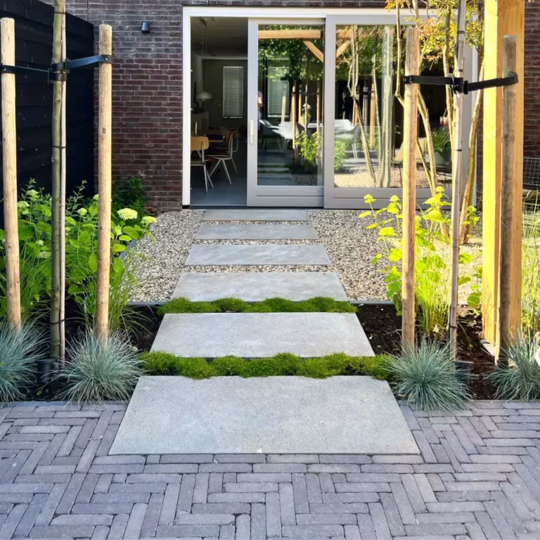 Tuinpad van grote stapplaten tussen grind en groen, terras van Tambour Mangaan in visgraat