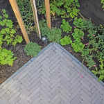Hoek van Tambour Mangaan waalformaat in visgraat met opsluitband naast border en tuinspot