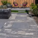 Terras met Tambour Smook klinkerpad, grote tegels, plantenbak en twee stoelen voor houten schutting