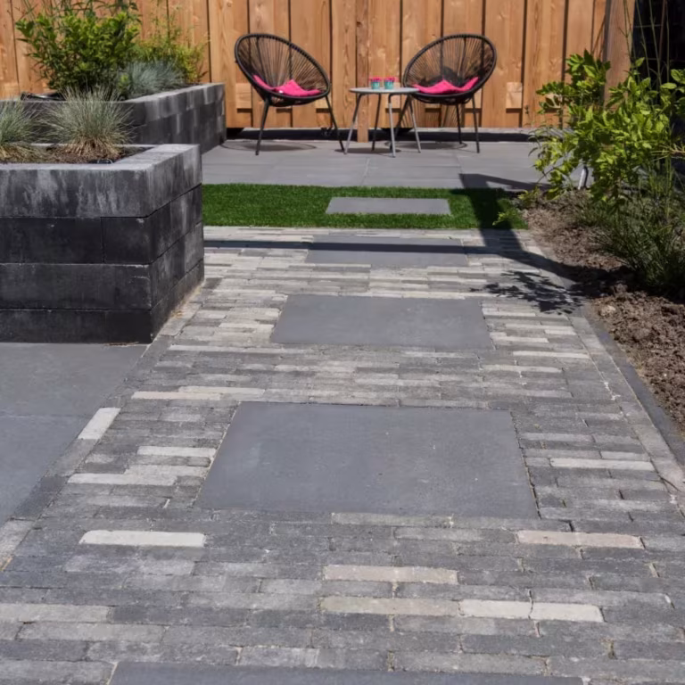 Terras met Tambour Smook klinkerpad, grote tegels, plantenbak en twee stoelen voor houten schutting
