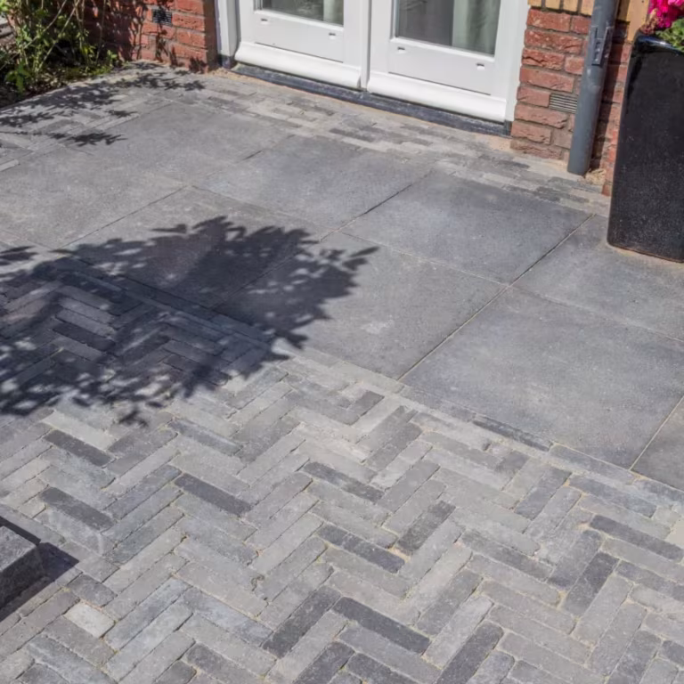 Schaduw van boom op grijze tegels en Tambour Smook klinkers in visgraatverband voor woning