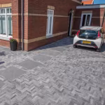 Oprit met Tambour Smook klinkers in visgraat en grote tegels voor baksteenwoning met auto