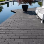 Antraciet betonklinkers 8 cm terras langs waterpartij met witte stoelen en sierboom in pot