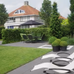 Terras met Soft Comfort Nero tegels, ligstoelen, buxusbollen en grasveld