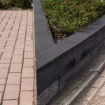Bestrating van roodbruine Tremico klinkers langs zwarte opsluitband met plantvak