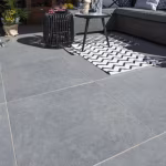 Terras met GeoCeramica Impasto Grigio tegels, loungebank, salontafel en zwart wit kleed
