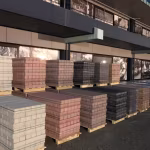 Pallets met betonklinkers in grijs, rood en zwart voor een bedrijfspand