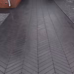 Oprit met Romano Punto Nero visgraatbestrating in zwart naar garagedeuren