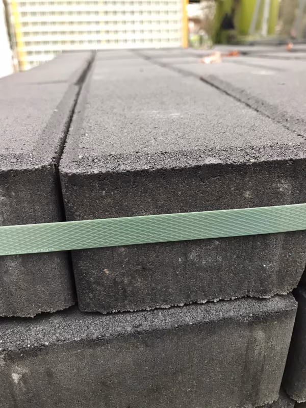Zijkant van gestapelde antraciet betonklinkers 8 cm met groene spanband