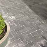 Tambour Antraciet in visgraatverband naast grote tegels, met buxus in schaal