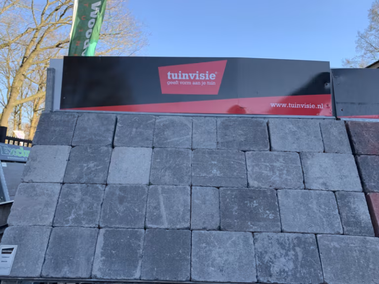 Tuinvisie showroomstaal met grijze Tambour Smook stenen tegen blauwe lucht