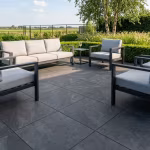 Terras met antraciet Cerasun Siena tegels, loungebank, fauteuils en strakke haag