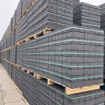 Rijen pallets met zwarte BSS betonklinkers 8 cm en groene spanbanden