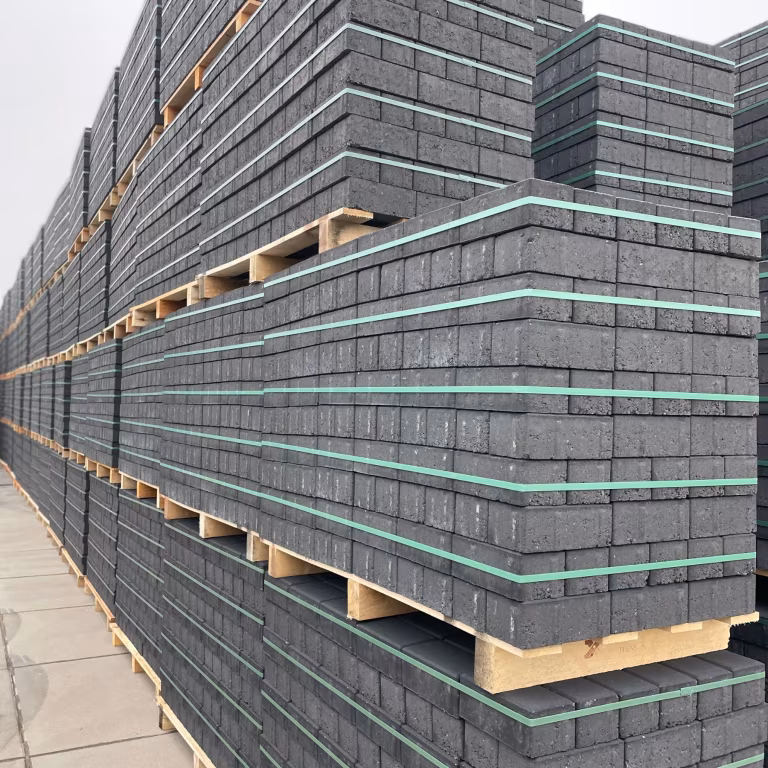 Rijen pallets met zwarte BSS betonklinkers 8 cm en groene spanbanden