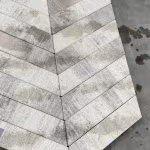 Close-up lichtgrijze Romano Punto visgraatstenen met natte vlekken