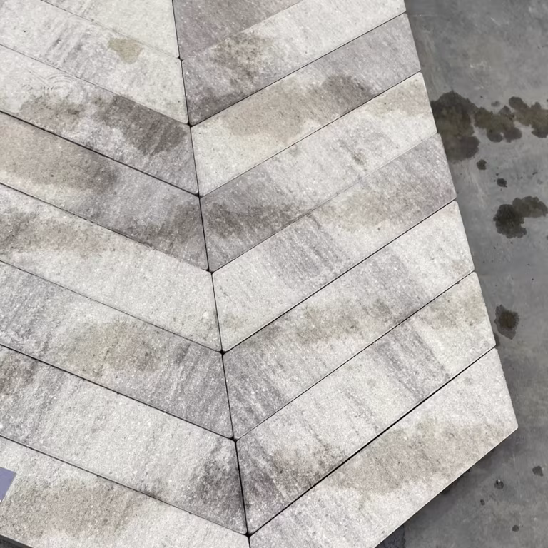 Close-up lichtgrijze Romano Punto visgraatstenen met natte vlekken