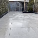 Smalle tuin met grote Piet Boon Outdoor Coast tegels, zwarte opsluitbanden en haag
