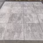 Terras van Trippel T 60x60x4 grijs nuance tegels met opsluitrand, schuin gefotografeerd