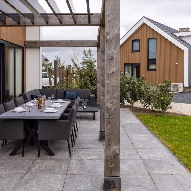 Gedekte eettafel en zitgroep onder pergola op GeoCorso Pescara tegels