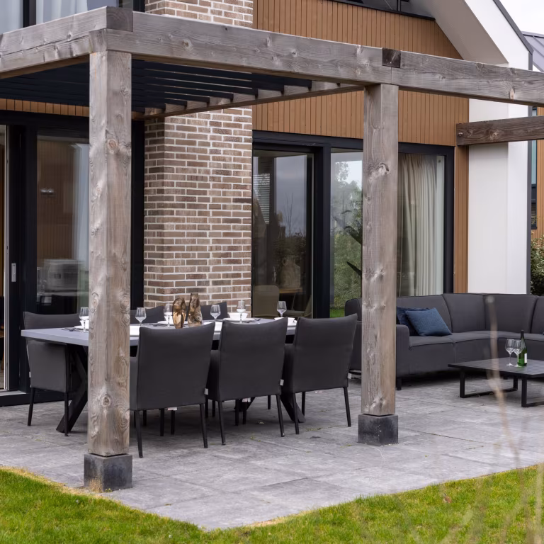 Pergola met zwarte tuinstoelen en eettafel op GeoCorso Pescara 60x60x4 tegels bij bakstenen pilaar