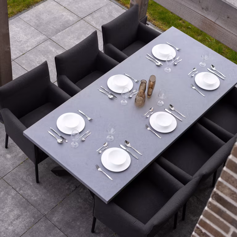 Bovenaanzicht gedekte eettafel met zwarte stoelen op GeoCorso Pescara tegels