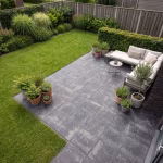 Terras met loungebank en potplanten op grijze Season Claude 60x60x4 Dusk tegels naast gazon