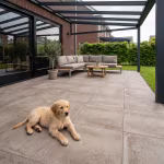 Overdekt terras met Season Claude 60x60x4 Sand tegels, loungeset en golden retriever pup
