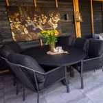 Zwarte eettafel met stoelen en bloemen op Soft Comfort Grezzo tegels onder overkapping