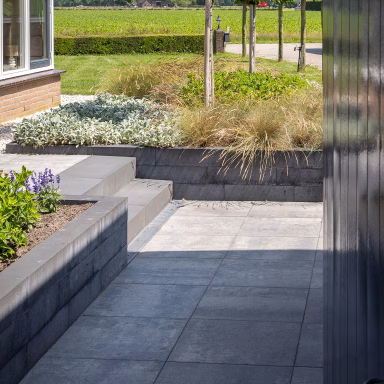 Soft Comfort Grezzo 60x60x4 tegels bij trap en lage muur langs gazon en tuinborder