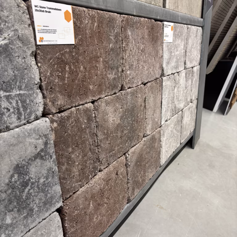 Showroomstaal getrommelde WG Stone Trommelsteen bruin naast grijze stenen met label