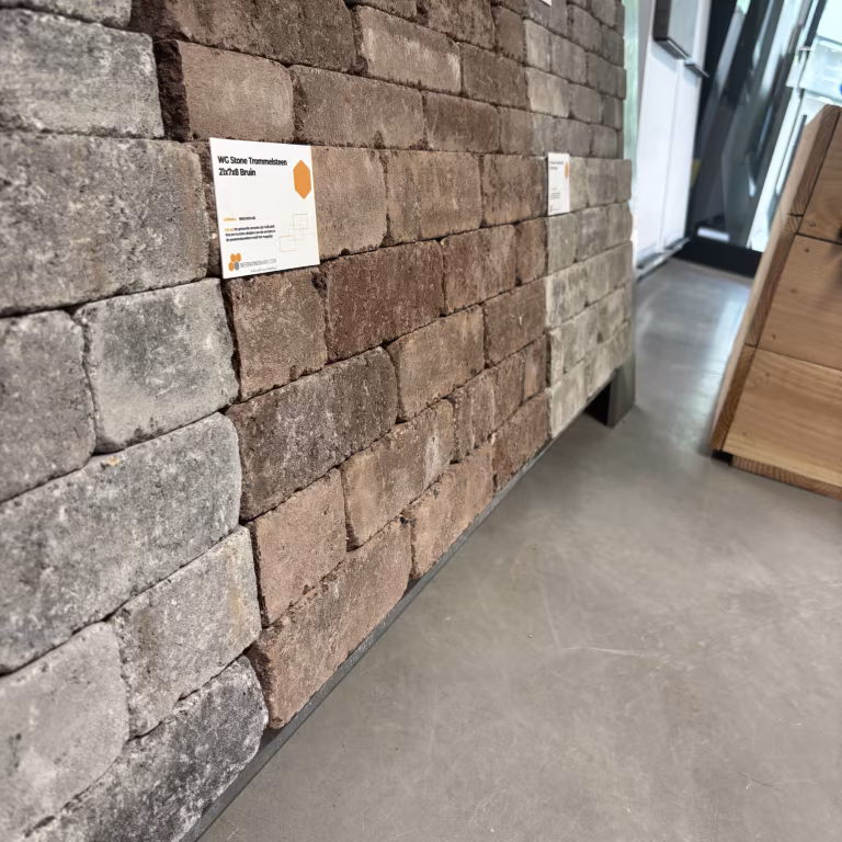 Showroomstalen WG Stone Trommelsteen bruin en grijs langs wand met label