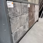 Showroomwand schuin gezien met grijze WG Stone Trommelsteen en bruine stenen met labels