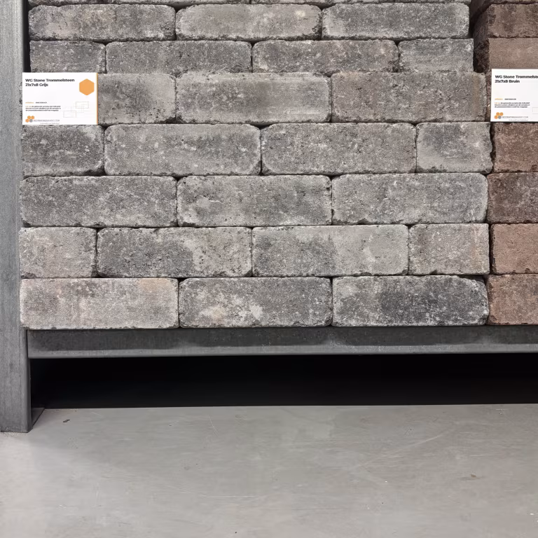 Showroomwand met gestapelde grijze WG Stone Trommelsteen 21x7x8 en artikellabel