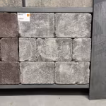 Showroomstaal WG Stone Trommelsteen 20x30x6 Taupe naast bruine stenen met artikellabel